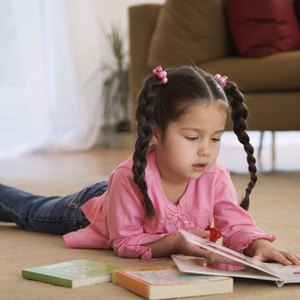 Young child reading book on floor